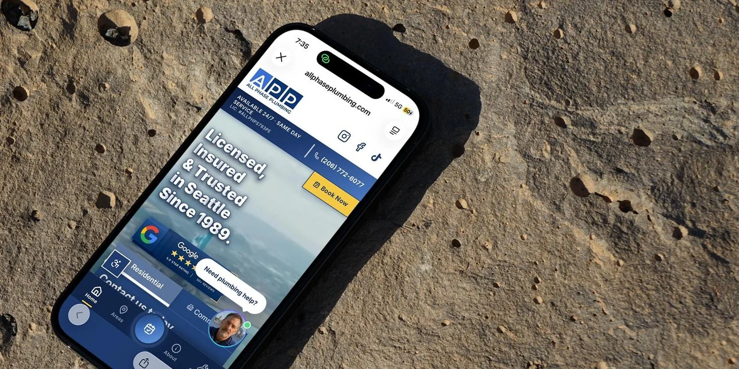 A phone showing the new site's homepage, resting on a stone surface